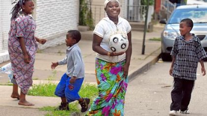 Amina Muya plays kickball with family members on the street outside their Lawrenceville home.