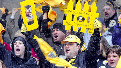 Mark McEwen holds up his "D-Fence" sign during yesterday's "Terrible Towel Wave" farewell to late Steelers broadcaster Myron Cope on the steps of the City-County Building, Downtown.
