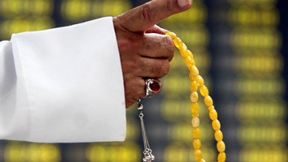 MANAMA, Bahrain --A stock trader holding prayer beads gestures in front of the trading board Monday, Oct. 13.