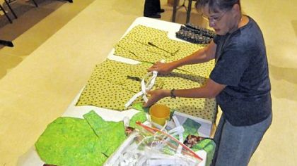 Mary Ann Rau, foreground, and Arlene Segar assemble kits of materials for sewers to use in making "Dignity Robes" worn by women undergoing cancer therapy.