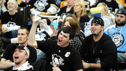 Penguins fan Kyle Stunkard, center, waves his towel as they watch the game via the jumbotron on the lawn at Mellon Arena.