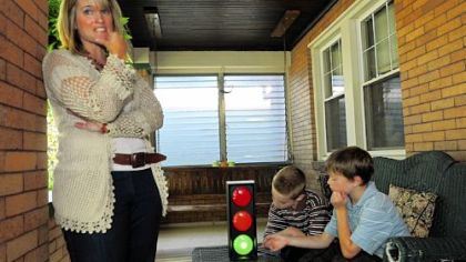 Heather Ditillo, left, explains her OneKindWord program as her sons, Theo, 8, center, and Logan, 10, look at the miniature traffic light she uses in her Family Resources Center sponsored program.