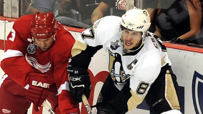 Sidney Crosby passes the puck around the Red Wings' Nicklas Lidstrom in the second period Monday at Joe Louis Arena in Detroit.