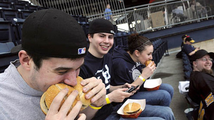 Jim Lewis, 21, of Coraopolis playfully stuffs two hamburgers in his mouth while his friend, Brenden Klink, 20, of West End, looks on at the all-you-can-eat section at the PNC Park during yesterday's Pirates-Cubs game. At right is their friend, Brittany Yourkonis, 19.