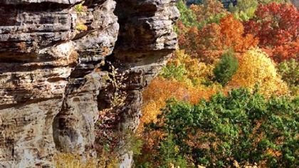 A towering sandstone cliff juts out into the fall colors of the gorge at Conkles Hollow in Hocking Hills State Park in Logan, Ohio.
