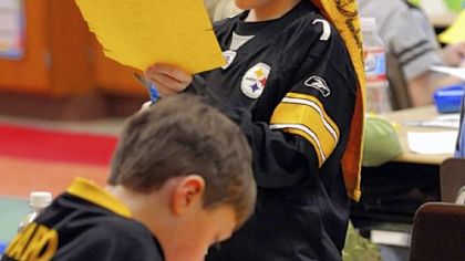First-graders Ryan Greer, left, and Max Sybert cut out paper Terrible Towels during class yesterday at Connoquenessing Valley Elementary School in Zelienople, where teachers, students and staff honored Myron Cope.