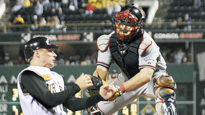 The Pirates' Brian Bixler slides into home plate to score the team's second run of last night's game as Atlanta Braves catcher Brian McCann misses the tag in the seventh inning at PNC Park.