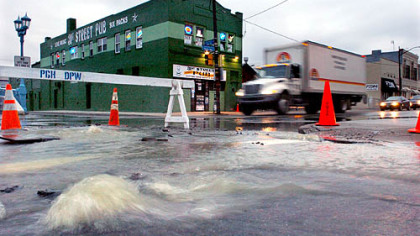 Two geysers squirt through the broken pavement over a water main break at 31st Street and Penn Avenue in the Strip District yesterday.
