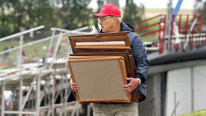 Coach Ed Thomas salvages team photos from the football office in the days after a tornado. But come Sept. 5, the season will go on.