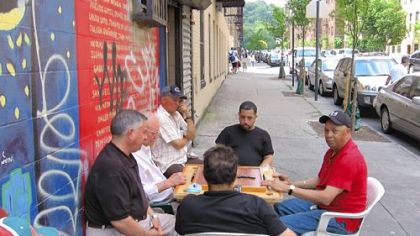 A group of men play dominoes on Ellwood Street in Washington Heights, New York City, a half block from Pedro Alvarez's apartment building.
