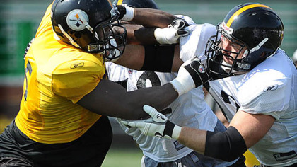 Center Justin Hartwig blocks defensive end Ryan McBean during morning workouts yesterday.