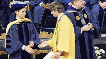 Chad S. Wilcox, center, with "Garrison Must Resign" taped to his mortarboard, walks past West Virginia University President Michael Garrison, right, without shaking his hand and greets honorary degree recipient Addison M. Fischer last night in Morgantown. Mr. Wilcox, a biology and history major, was one of two honors students who protested against Mr. Garrison at their graduation ceremony at the WVU Coliseum last night. Mr. Garrison, subject of no-confidence votes by the faculty over a degree scandal involving the daughter of West Virginia Gov. Joe Manchin, attended the ceremony but did not speak. Many of the 130 honors graduates shook the president's hand as they crossed the stage to get their diplomas.