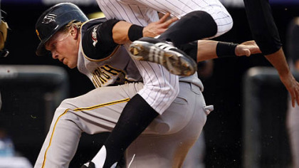 Nate McLouth, left, slides under the tag of Rockies starting pitcher Ubaldo Jimenez to score on a passed ball in the third inning last night in Denver.(AP Photo/David Zalubowski)