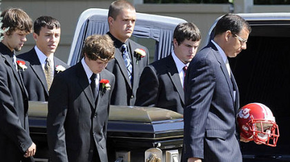 Pallbearers carry the casket of John Challis and his Freedom football helmet yesterday into SS. Peter and Paul Roman Catholic Church in Beaver for his funeral.