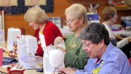 Margie McGinn, left, of Murrysville, Jean Laverty, of Lower Burrell, and Maire Machens, of Murrysville, sew holiday stockings to be filled with treats and sent to soldiers abroad at Gloria Horn Sewing Studio in Monroeville.