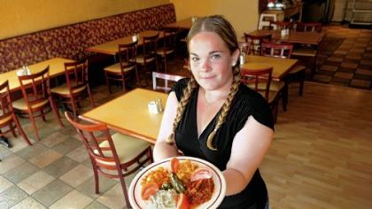 Istanbul Grille waitress Sarah Williams holds a plate with two grape leaves stuffed with rice, red beans, Tabbouleh, spicy vege and baba ghanoush.