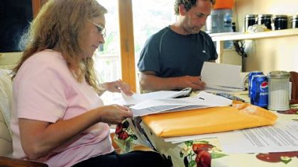 Cindy and Randy Balzer, sitting in the kitchen of their Baldwin Township home, look over stacks of paperwork as they try to save their home from foreclosure.