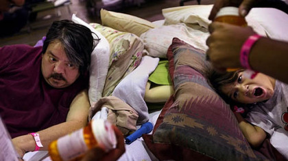 DALLAS -- Rain Foreman, 6, yawns as her mother, not shown, discusses medical care with a medical student from University of Texas Southwestern at the temporary hurricane evacuee shelter at the Dallas Convention Center. Raymond Cerda, left, of Beaumont, Tx. suffers from seizures that can be environmentally triggered since he has a decades old head injury.