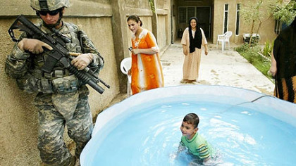 BAGHDAD -- A US soldier walks past an Iraqi child playing in the residential courtyard.
