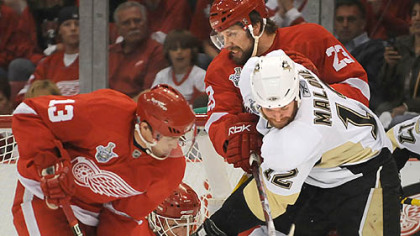 Red Wings goalie Chris Osgood gets help from a few friends in keeping Ryan Malone at bay last night.