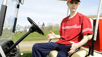 At his team's baseball game, John Challis uses a golf cart to get around.