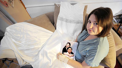 Melody Luchuck sits in her apartment with her wedding dress across her lap, holding a photo of herself with her fiance, Eduardo Vielma, who's awaiting deportation.