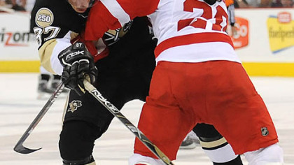 Sidney Crosby is held up by the Red Wings' Brian Rafalski in the third period.