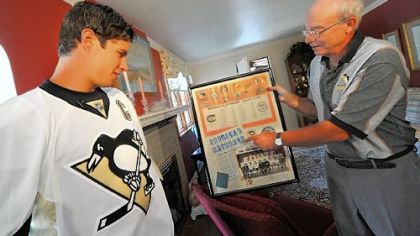 Sidney Crosby is shown the score sheet from 1967 by lifelong season-ticket holder David Disney after Crosby delivered Disney's season tickets yesterday. It marks the second season Penguins players helped deliver the tickets to their fan base.