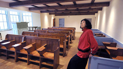 E. Maxine Bruhns leans on the "box pews"  in the Welsh Nationality Classroom.