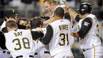 Jason Michaels leaps onto home plate as his Pirates teammates surround him in the aftermath of him hitting a game-winning home run last night against the Cardinals.