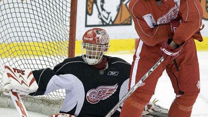 Detroit right winger Johan Franzen battles for the puck with goaltender Dominik Hasek yesterday in practice. Franzen could return to the Red Wings' lineup for Game 2 in Detroit tonight.