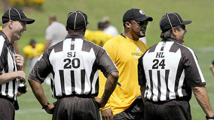 Coach Mike Tomlin talks to NFL referees during training camp Thursday.