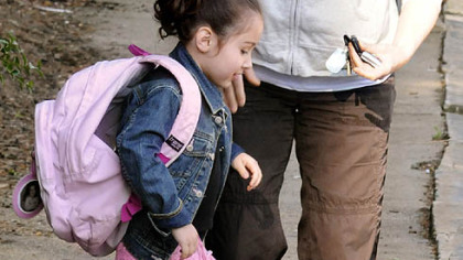 Tracy Royston helps her daughter Maya with her backpack in front of John Minadeo Elementary School in Squirrel Hill yesterday. Maya is in the pre-kindergarten program. Ms. Royston normally drives her to school.