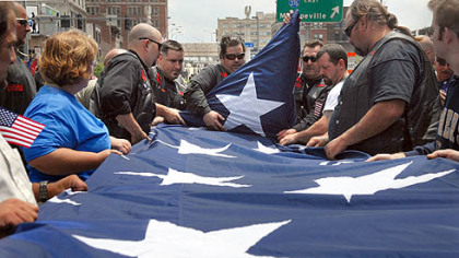 Members of the War Dogs motorcycle club fold the large flag they carried during the  rededication ceremony for the Boulevard of the Allies.