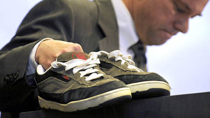 While addressing the National Symposium on Handgun Violence at Duquesne University, Tom Mauser displays the shoes of his son, Daniel, who was killed at Columbine High School. Mr. Hauser wears the shoes on special occasions.