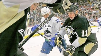 Max Talbot, left, and Jordan Staal battle for the puck with the Canucks' Rob Davison in the second period yesterday at Mellon Arena.