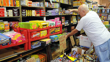 Bill McCoy of McKeesport, straightens the shelves piled with candy at the Fort Pitt Candy Company in the Strip.