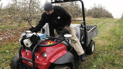 Brad Hamne, of Baton Rouge, La., checks the sensors on the front of a  electric golf cart with robotic technology to help monitor trees  at Soergel Orchards.