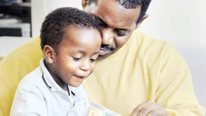 Melvin Harris and his grandson Kalaun, 2, take time from the Carnegie Library of Pittsburgh Hill District grand-opening celebrations to check out a book yesterday.