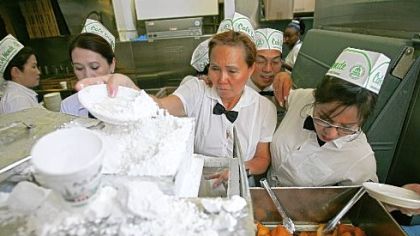 Waitresses prepare beignets covered with powdered sugar at Cafe du Monde, one of the most popular tourist spots in New Orleans' French Quarter.